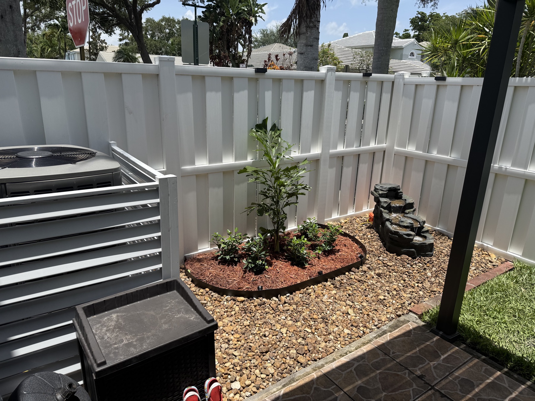 Finished backyard corner with dwarf fishtail palm, Green Island ficus, and rock waterfall fountain running
