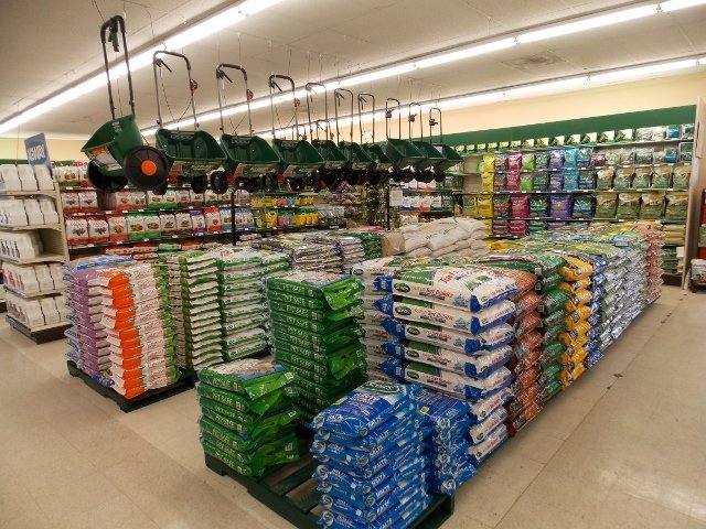 Fertilizer aisle at a home improvement store — bags of Scotts, Spectracide, and more stacked floor to ceiling
